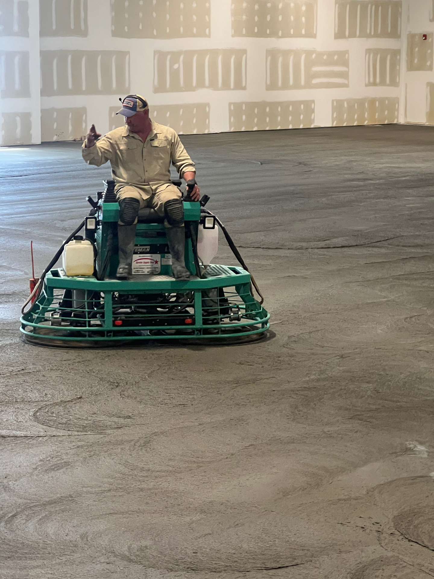 Operator finishing a concrete floor with a ride-on power trowel